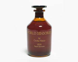 Photo of a brown glass bottle etched in gold with the text, "WORLD SENSORIUM by Gayil Nalls, 1999 First Edition